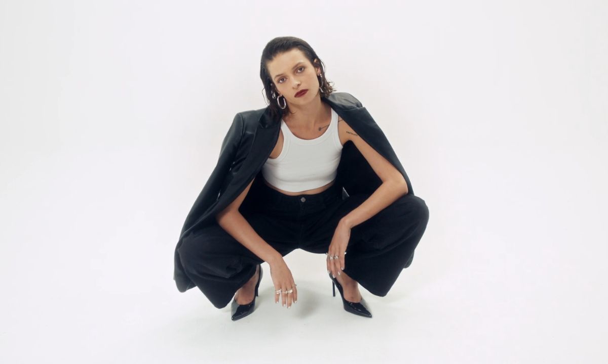 devojka u crnom sakou, beloj majici i crnim pantalonama pozira