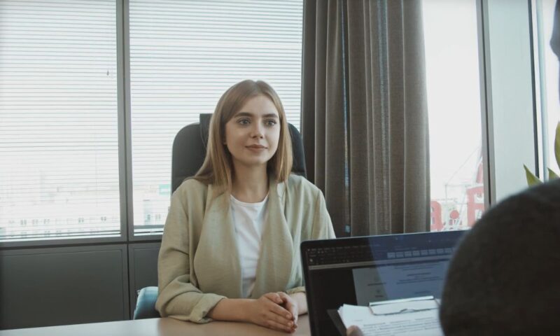 devojka u sakou i belooj majici sedi u kancelariji