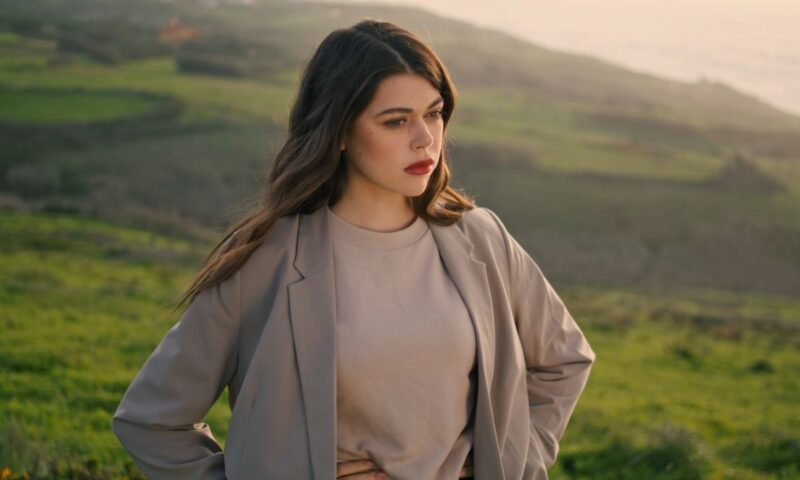 devojka obučena u krem duks i sako pozira u prirodi