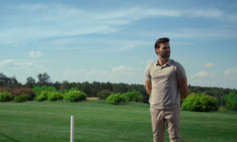 momak pozira u polo majici i krem pantalonama